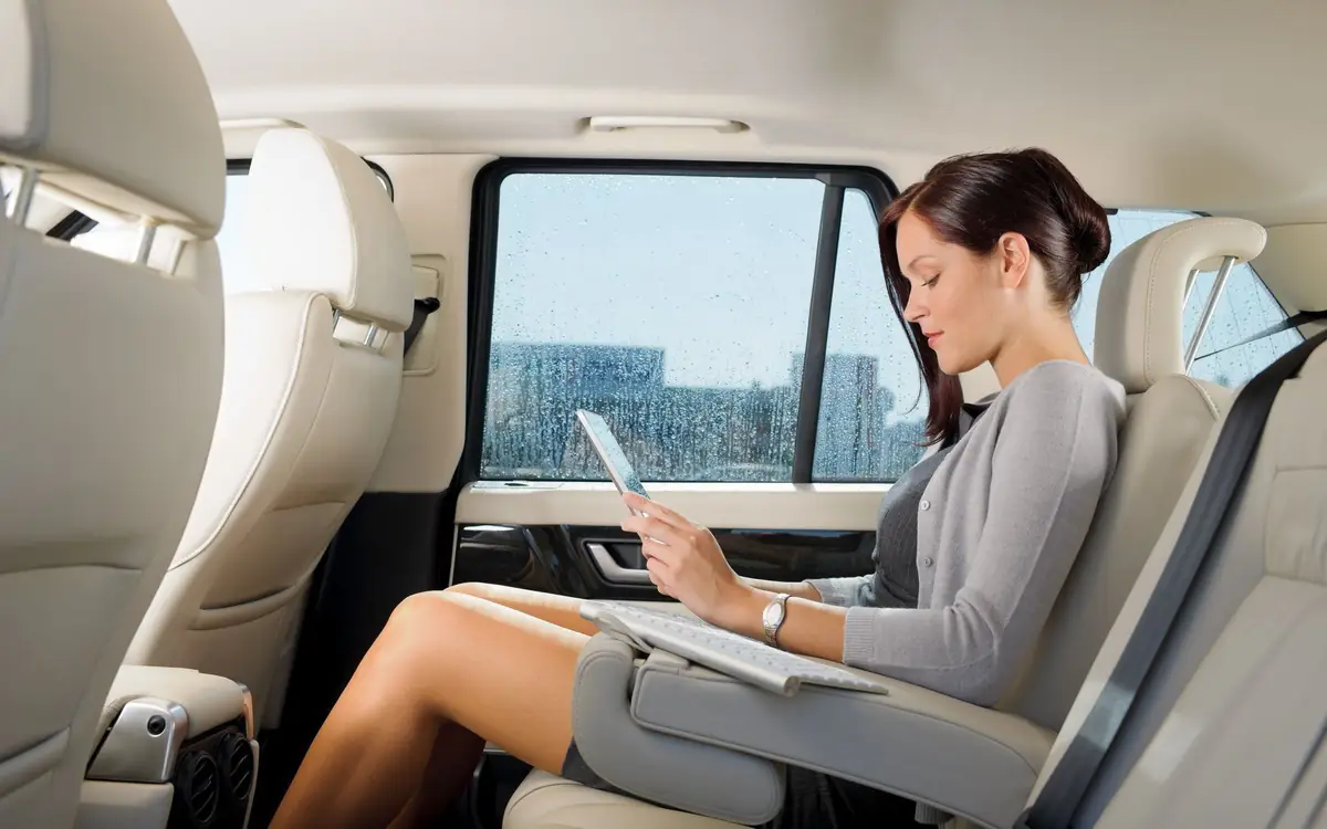 Businesswoman reading a tablet in the back seat of a chauffeured car